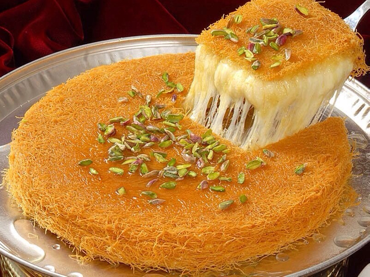 "Indulge in the rich and creamy Middle Eastern dessert sensation with our mouthwatering Kunafa! A crispy pastry filled with melted cheese and soaked in sweet syrup, topped with crunchy pistachios. Perfect for any occasion and sure to satisfy your sweet cravings. Click now to order and experience the authentic taste of Kunafa right at your doorstep